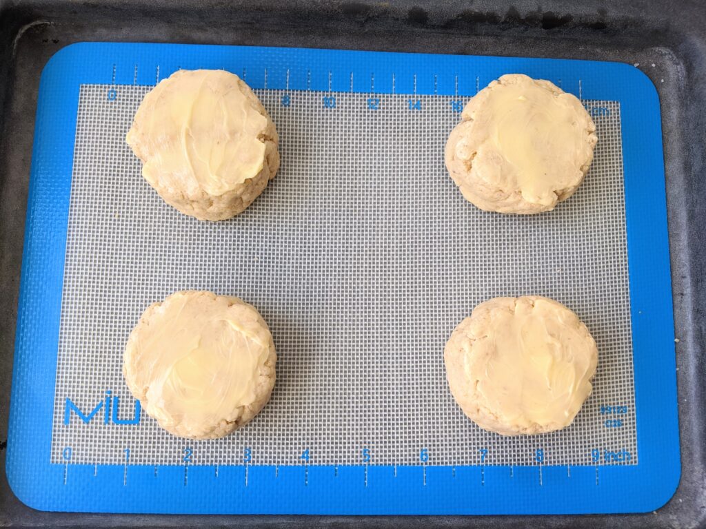 biscuits topped with butter and ready to bake